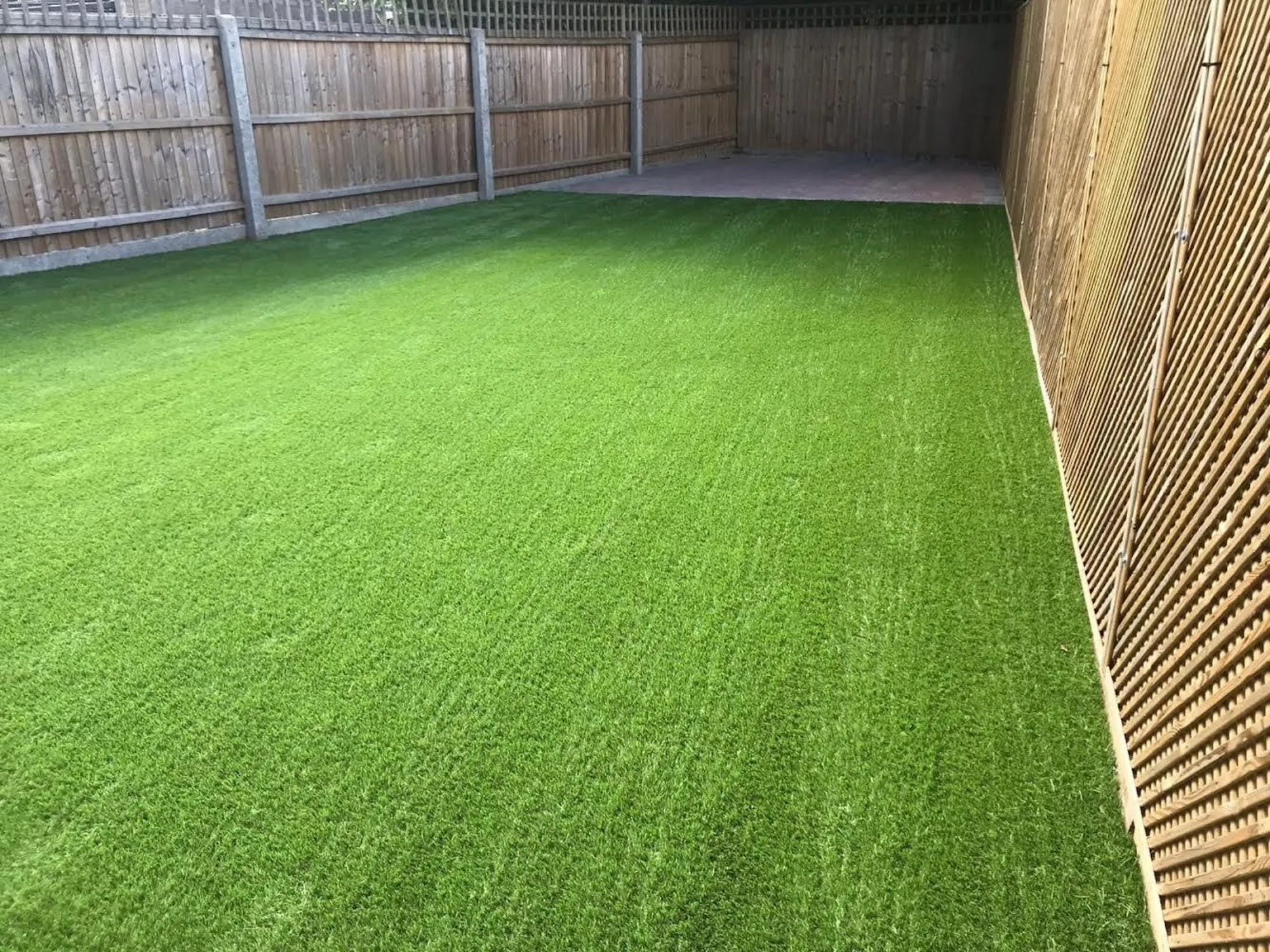 Patios 8 Artificial Grass newly installed up to fence line line.