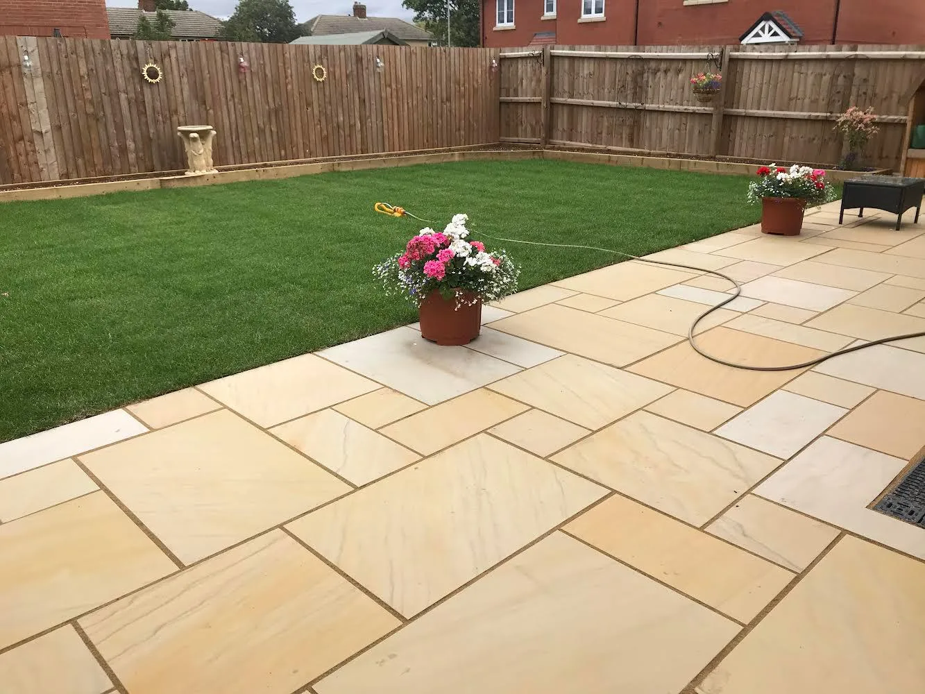 An image showing a brand new lush green lawn and yellow tinted patio